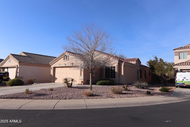 view of front of house with a tile roof, driveway, an attached garage, and stucco siding