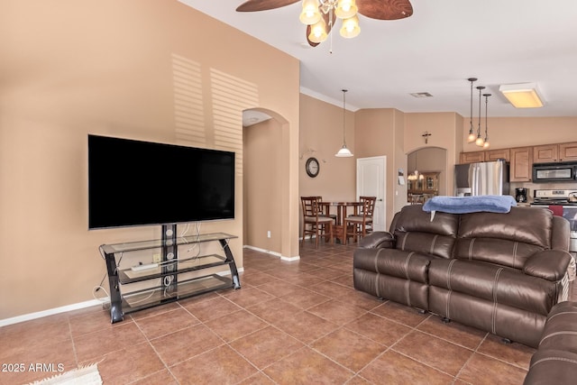 living room featuring light tile patterned floors, ceiling fan, visible vents, and arched walkways