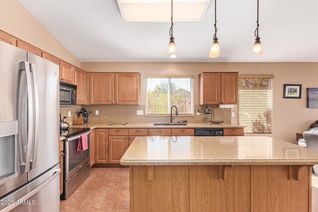 kitchen with a breakfast bar area, a sink, black appliances, light stone countertops, and backsplash