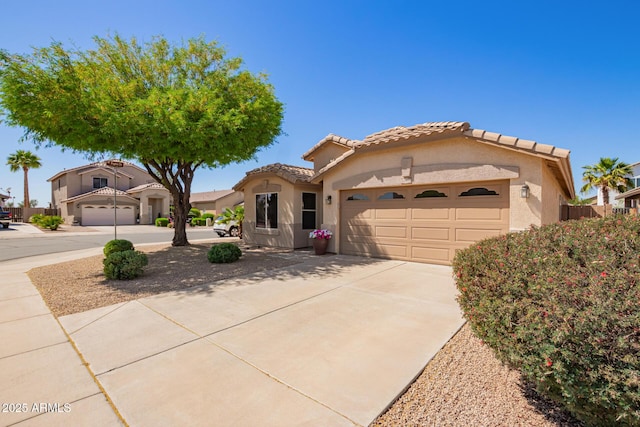 mediterranean / spanish house featuring a garage, concrete driveway, stucco siding, and a tiled roof