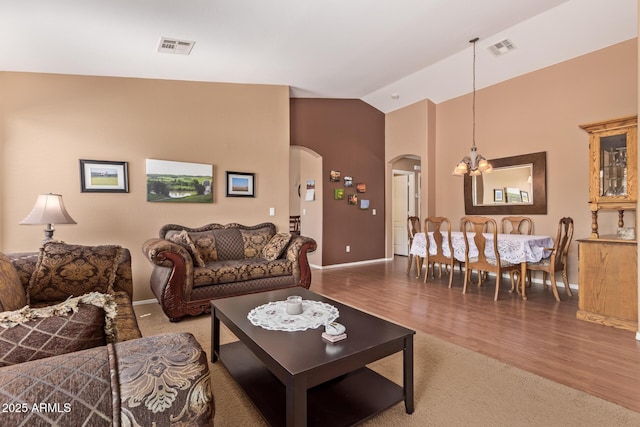 living room with wood finished floors, visible vents, baseboards, and arched walkways