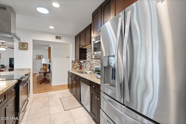 kitchen with appliances with stainless steel finishes, range hood, sink, light stone countertops, and dark brown cabinets