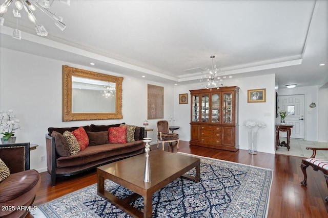 living room featuring a tray ceiling, dark wood-type flooring, and a chandelier