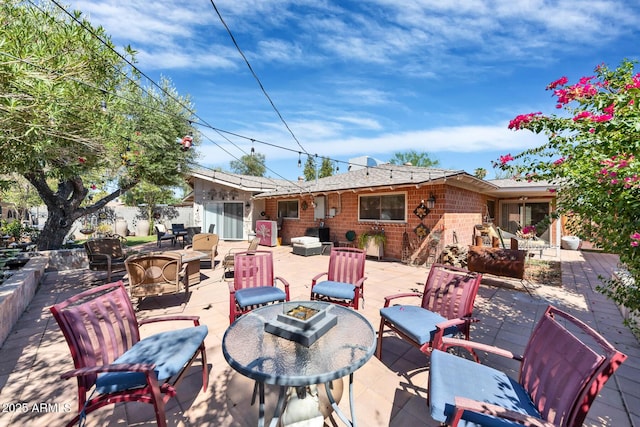 rear view of house featuring a patio area, brick siding, and a fire pit