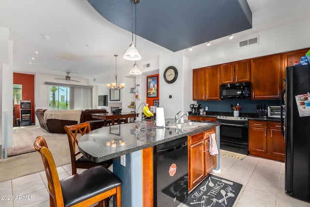 kitchen featuring pendant lighting, black appliances, a kitchen breakfast bar, a center island with sink, and sink