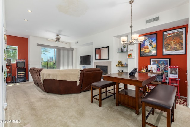 dining room with a fireplace, ceiling fan with notable chandelier, and light colored carpet