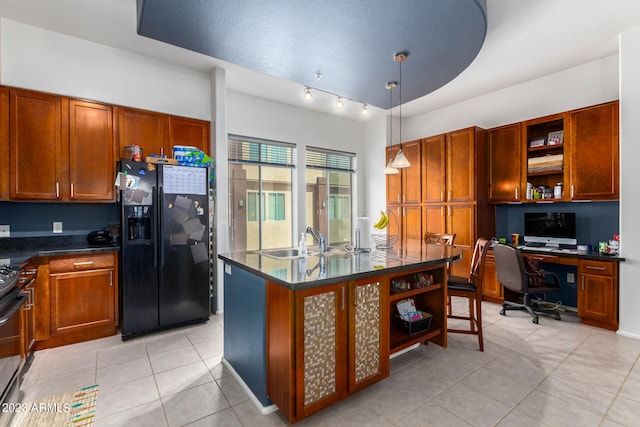 kitchen featuring sink, hanging light fixtures, light tile patterned floors, built in desk, and black fridge with ice dispenser