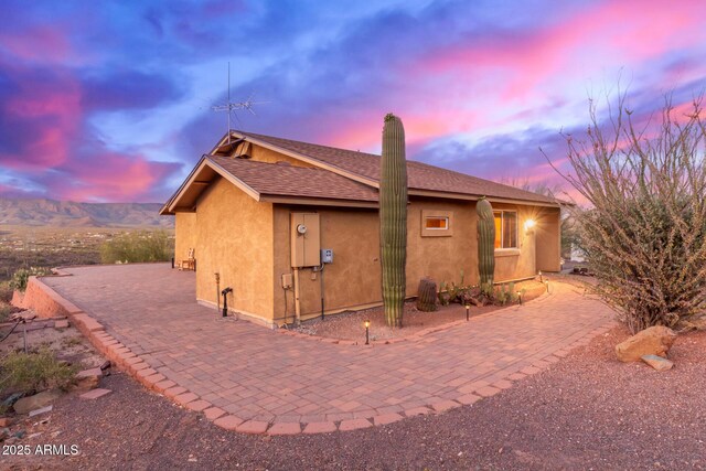 43911 N 13th Ave, New River, AZ 85087 - back of house at dusk featuring stucco siding, a patio area, roof with shingles, and a chimney