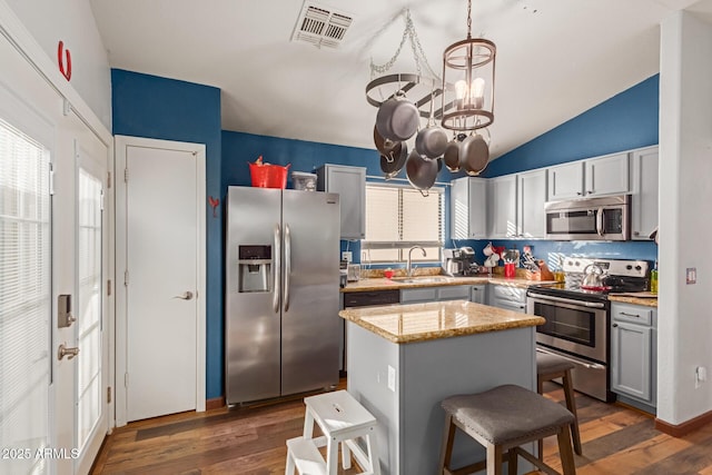 kitchen with a center island, sink, vaulted ceiling, stainless steel appliances, and a chandelier