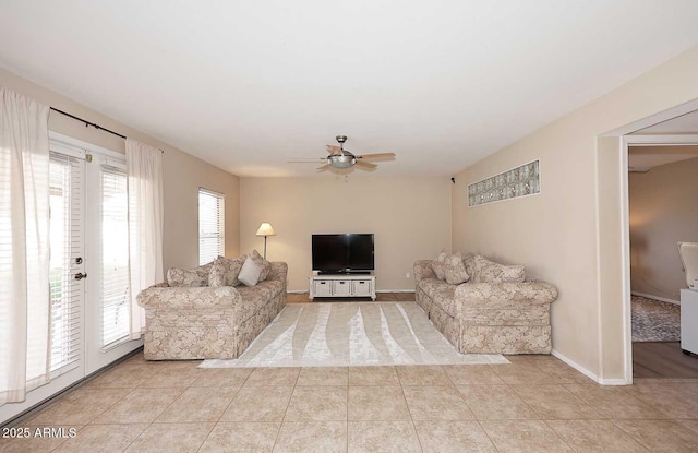 living room featuring light tile patterned floors, a ceiling fan, and baseboards