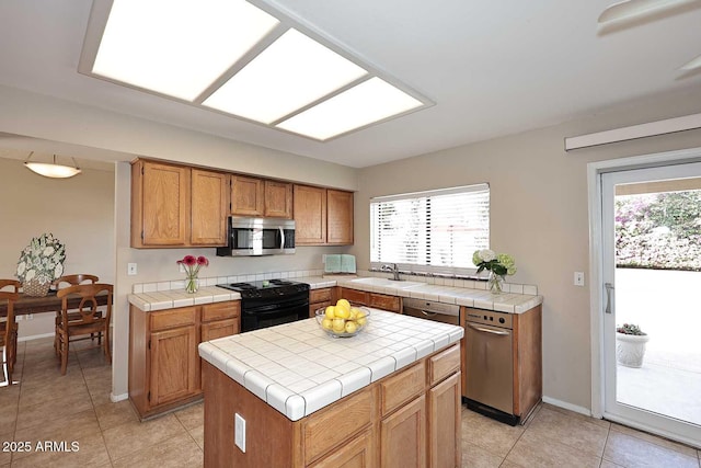 kitchen featuring electric range, a kitchen island, a sink, tile counters, and stainless steel microwave