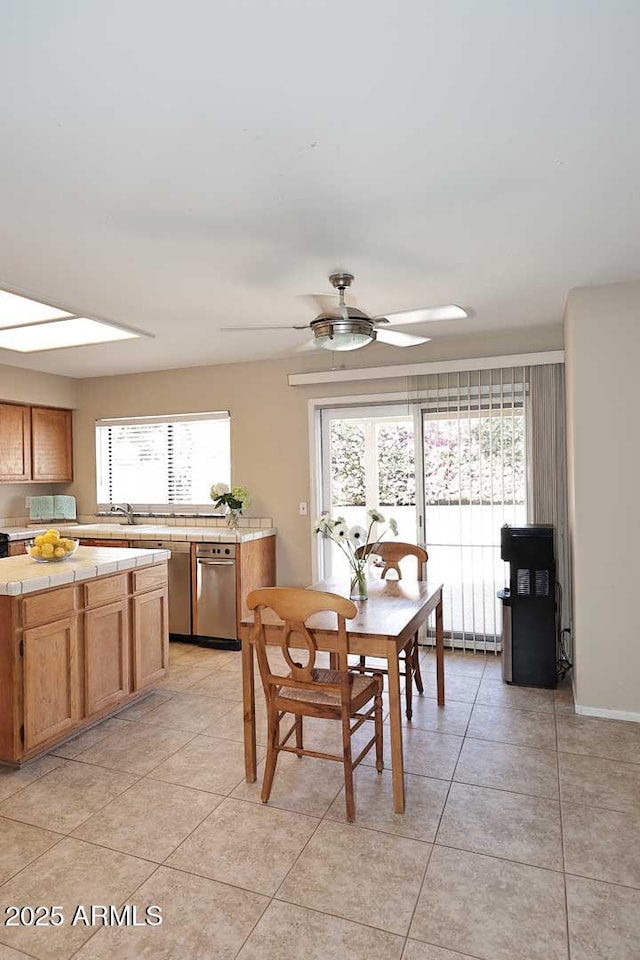 dining room featuring ceiling fan, a baseboard radiator, light tile patterned flooring, a skylight, and baseboards