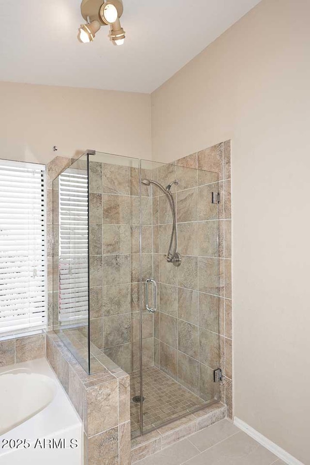 bathroom featuring a stall shower, a garden tub, and baseboards