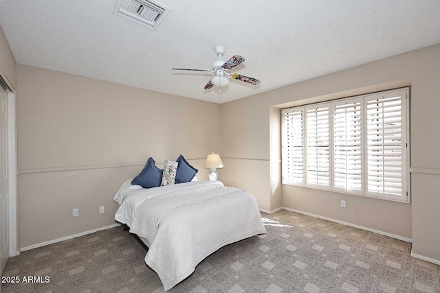 bedroom featuring carpet floors, visible vents, a textured ceiling, and baseboards