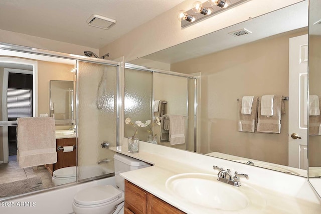 bathroom with visible vents, vanity, toilet, and bath / shower combo with glass door