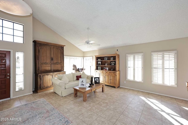 living room with a ceiling fan, light tile patterned flooring, a textured ceiling, and baseboards