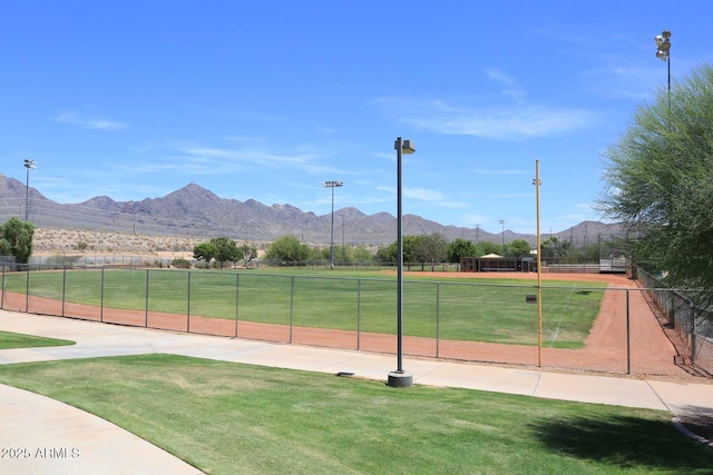 surrounding community with fence, a mountain view, and a lawn