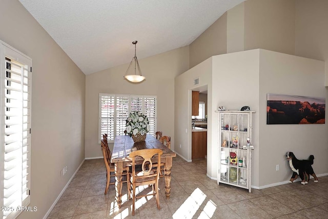 dining space with high vaulted ceiling, a textured ceiling, baseboards, and light tile patterned floors