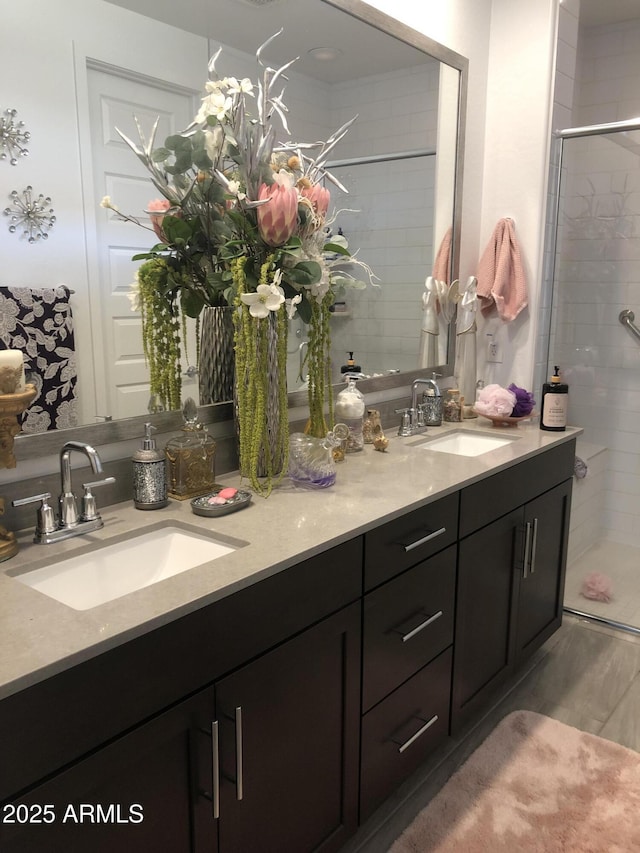 bathroom with a sink, wood finished floors, a stall shower, and double vanity