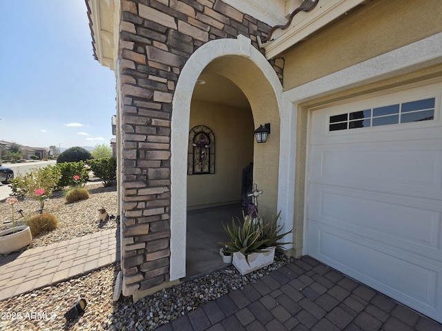 doorway to property featuring stucco siding and a garage