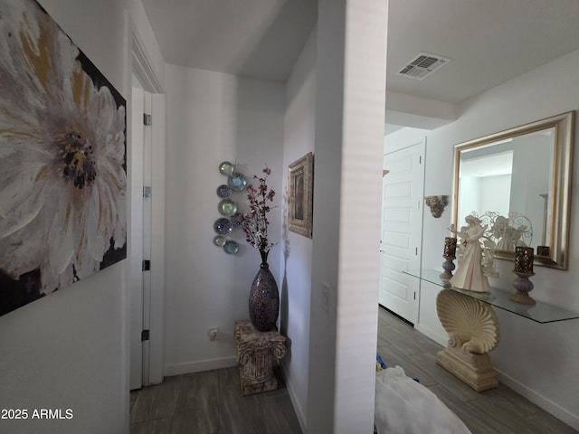 corridor featuring visible vents, baseboards, and wood finished floors