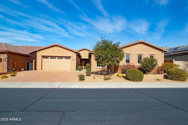 view of front of home featuring a garage, a tile roof, decorative driveway, and stucco siding