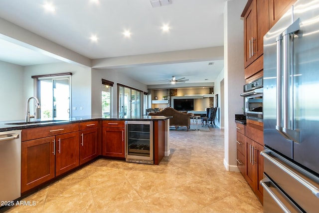 kitchen featuring appliances with stainless steel finishes, wine cooler, a sink, and brown cabinetry