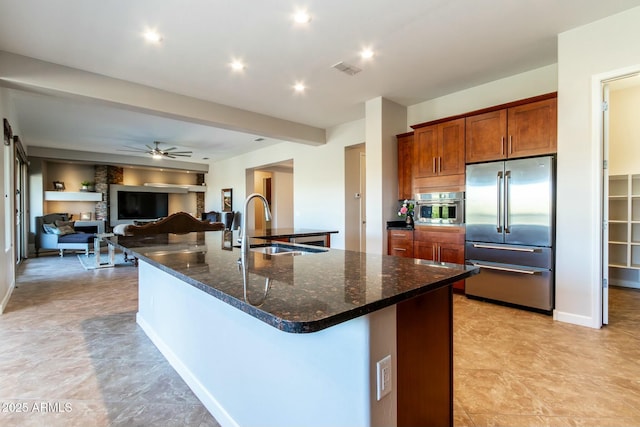 kitchen featuring visible vents, a large island, high end fridge, a sink, and recessed lighting