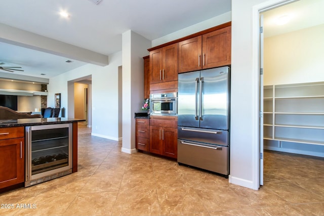 kitchen featuring baseboards, dark stone counters, ceiling fan, wine cooler, and stainless steel appliances