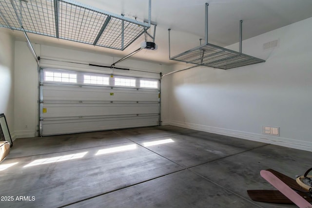 garage with a garage door opener, visible vents, and baseboards