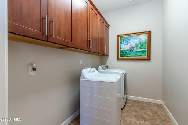 washroom featuring cabinet space, baseboards, and washer and clothes dryer