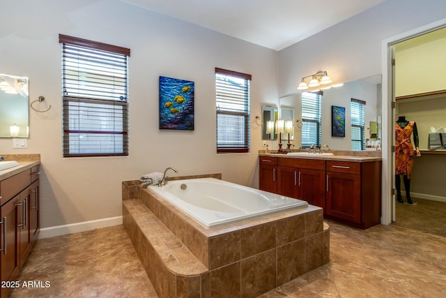 full bathroom with two vanities, a sink, a bath, and baseboards