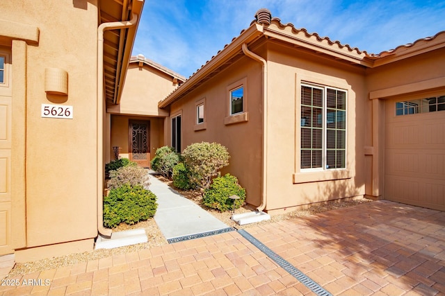 doorway to property featuring a tile roof and stucco siding