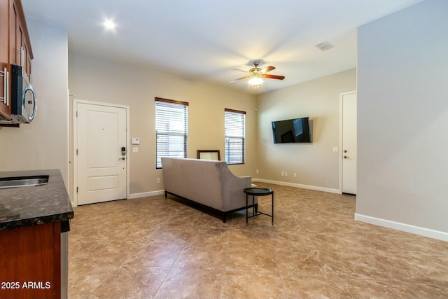 living room featuring ceiling fan, visible vents, and baseboards