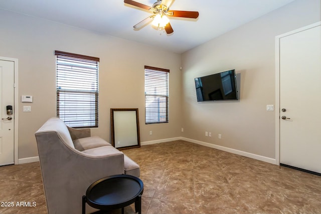 living area with ceiling fan and baseboards