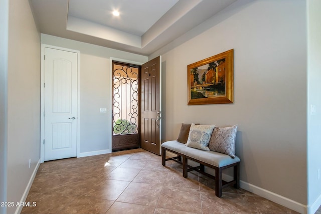 entryway with a tray ceiling and baseboards