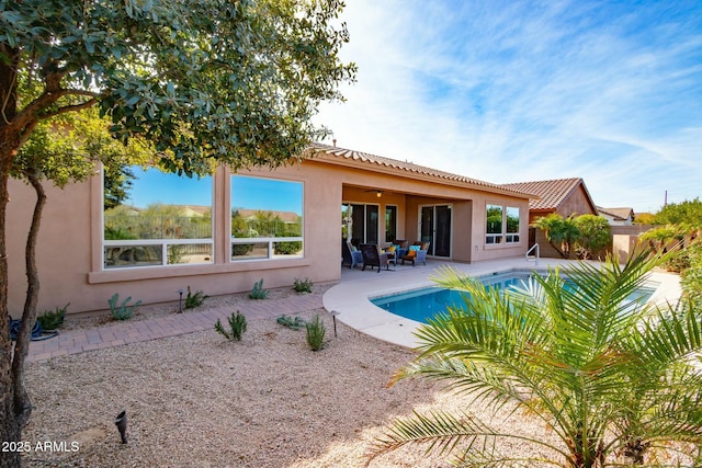 rear view of property featuring ceiling fan, a patio, a tiled roof, an outdoor pool, and stucco siding