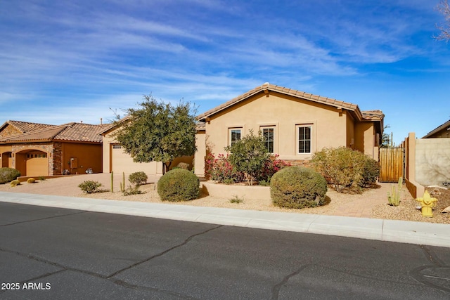 view of front of house featuring a garage, fence, a tile roof, driveway, and stucco siding