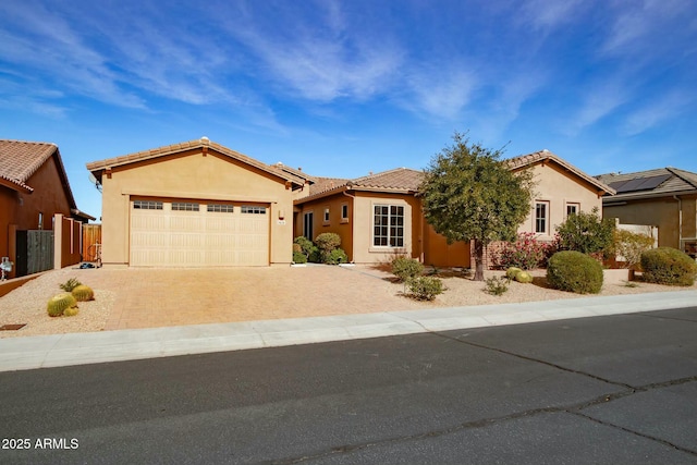 ranch-style house with an attached garage, fence, a tiled roof, decorative driveway, and stucco siding