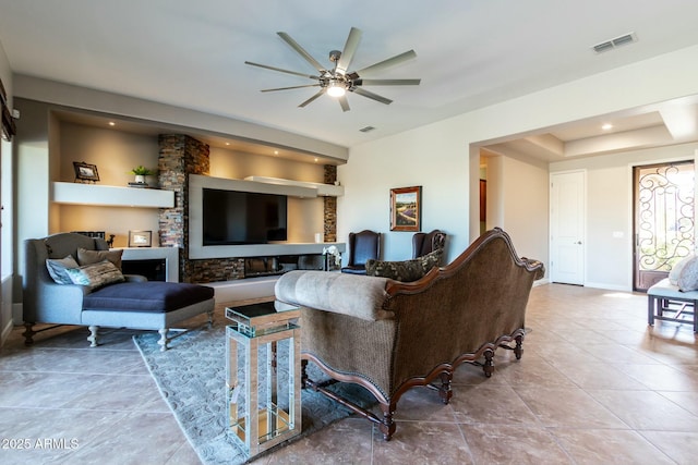 tiled living room featuring visible vents, ceiling fan, and baseboards