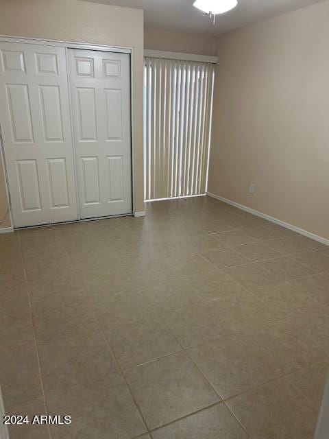 unfurnished bedroom with a closet, baseboards, and tile patterned floors