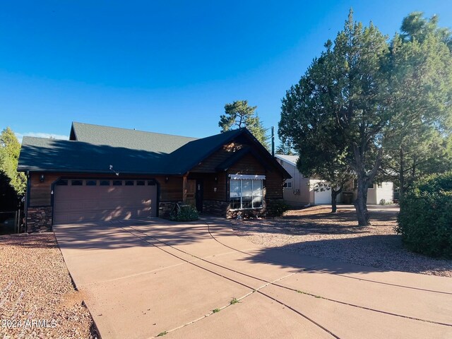 view of front facade featuring a garage, stone siding, and driveway