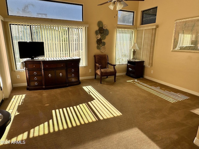 living area with dark colored carpet, ceiling fan, and a healthy amount of sunlight