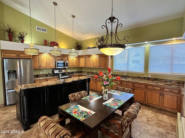 kitchen with a center island, high vaulted ceiling, dark stone counters, appliances with stainless steel finishes, and decorative light fixtures