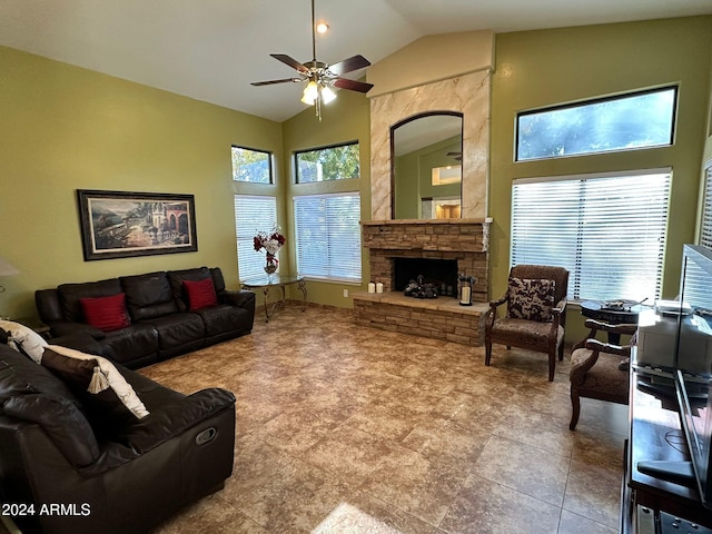 living room with high vaulted ceiling, a stone fireplace, plenty of natural light, and ceiling fan