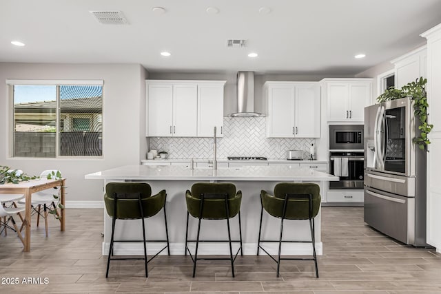 25725 S 230th St, Queen Creek, AZ 85142 - kitchen with wall chimney exhaust hood, light wood finished floors, stainless steel appliances, and visible vents