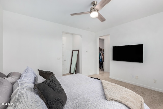 carpeted bedroom featuring a walk in closet, a closet, and ceiling fan