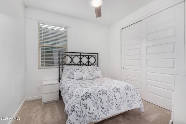 bedroom featuring light colored carpet, a closet, and ceiling fan