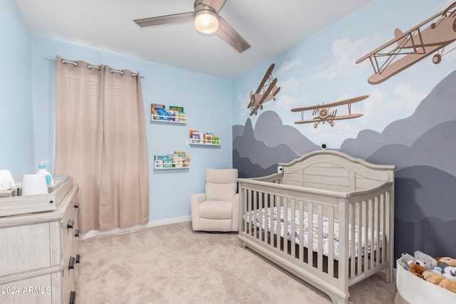 carpeted bedroom featuring a nursery area and ceiling fan