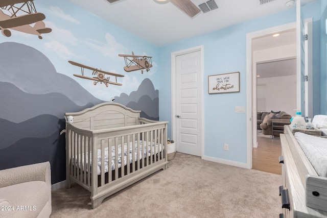 carpeted bedroom with a nursery area and ceiling fan